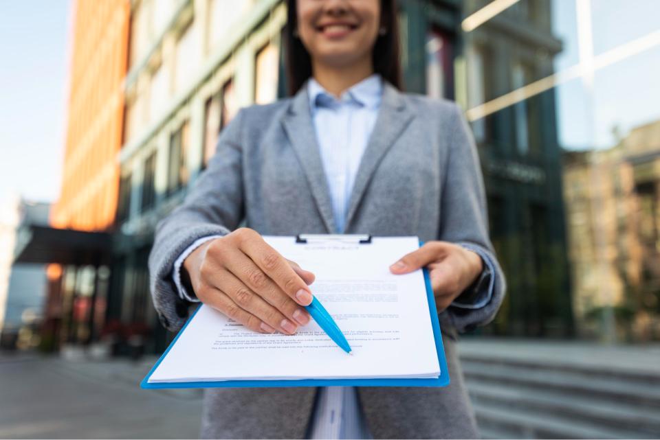 mulher em frente a um prédio solicitando assinatura em um documento